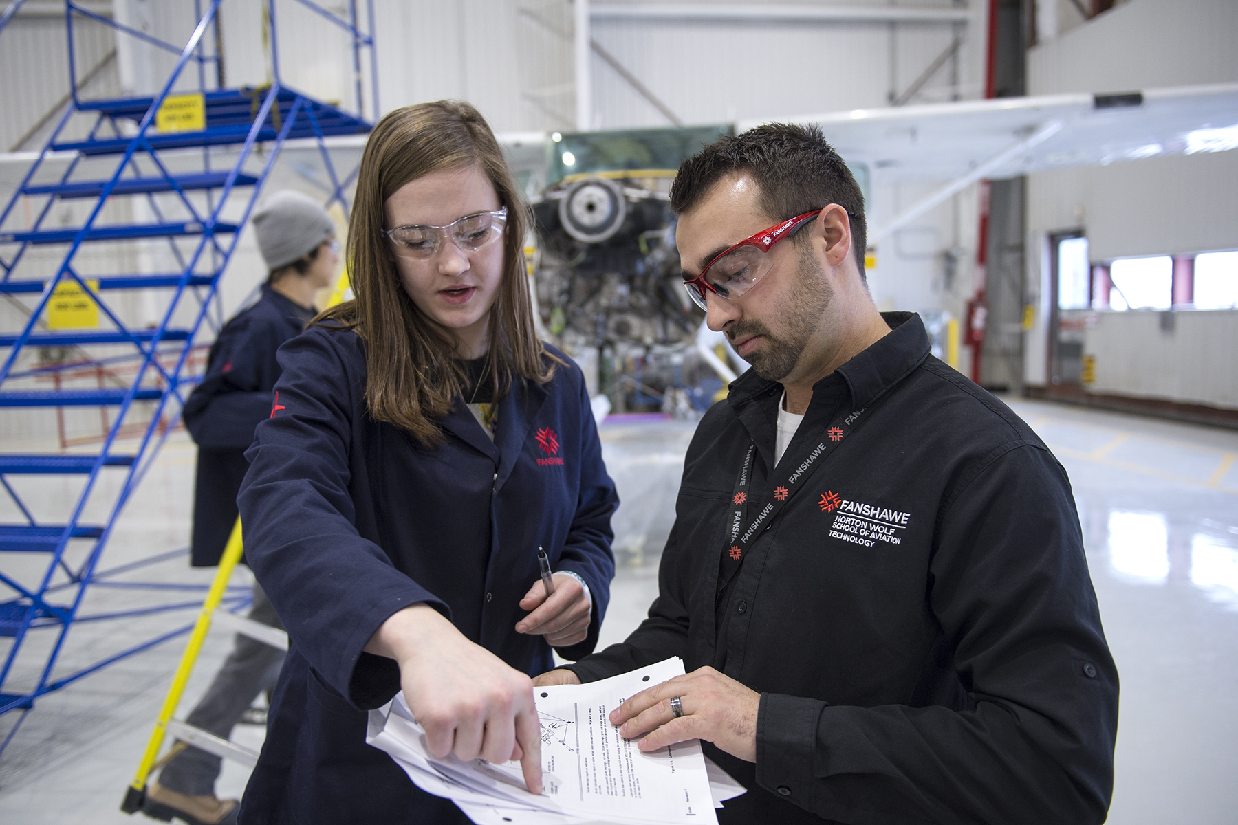 An instructor reviewing aviation information with a student in a flight hanger