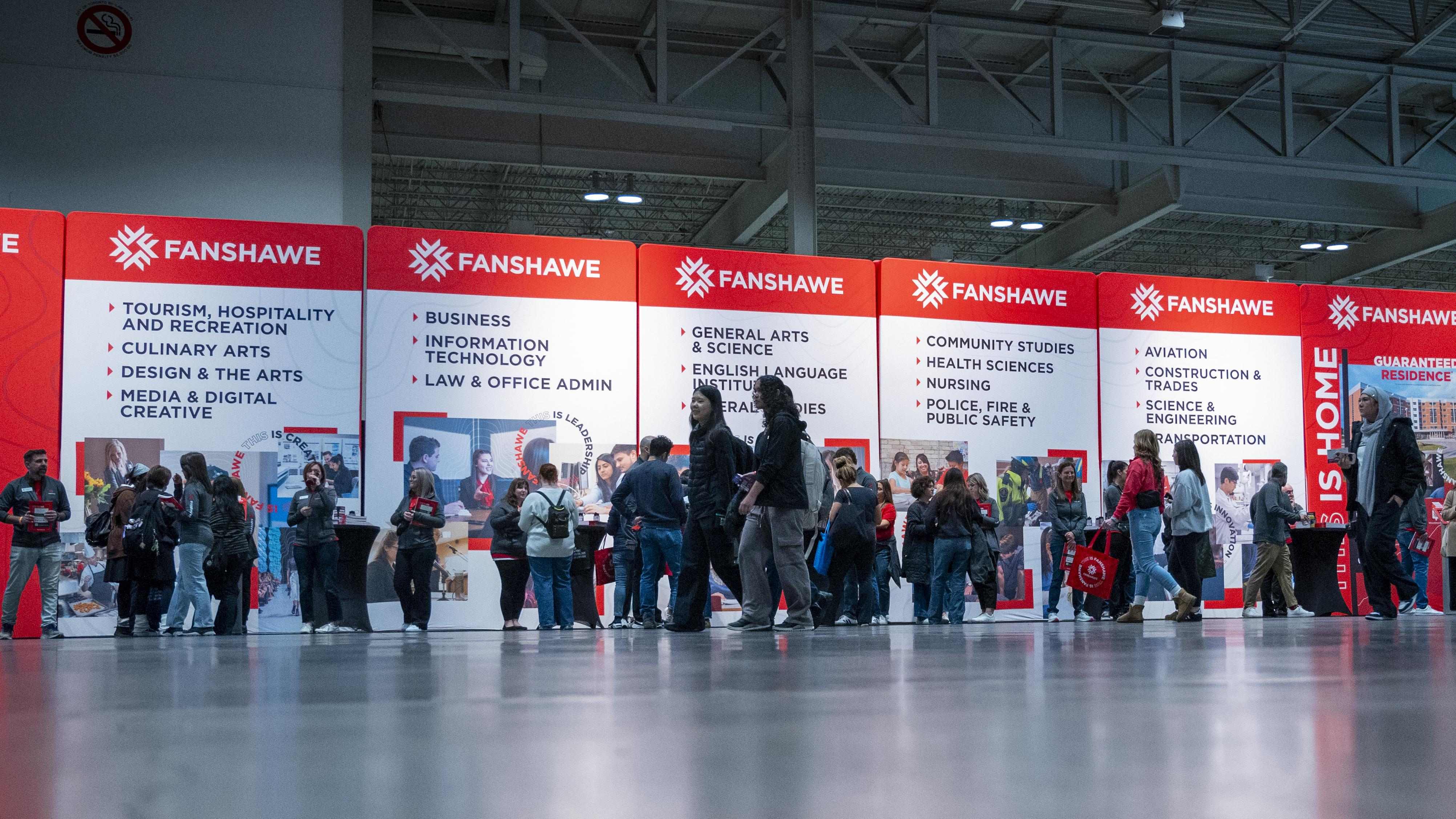 prospective students explore fanshawe programs in front of signs for areas of study