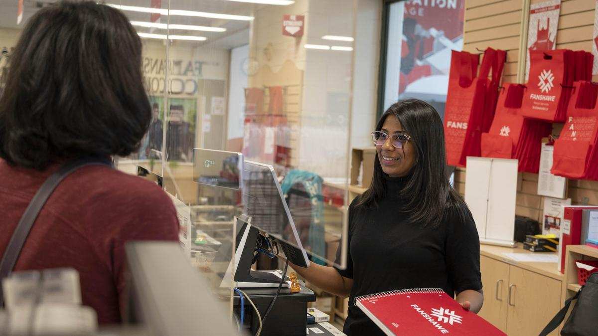 retail worker hands product to customer