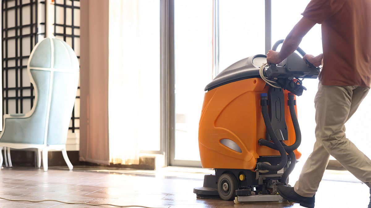 person pushes floor cleaner through hallway