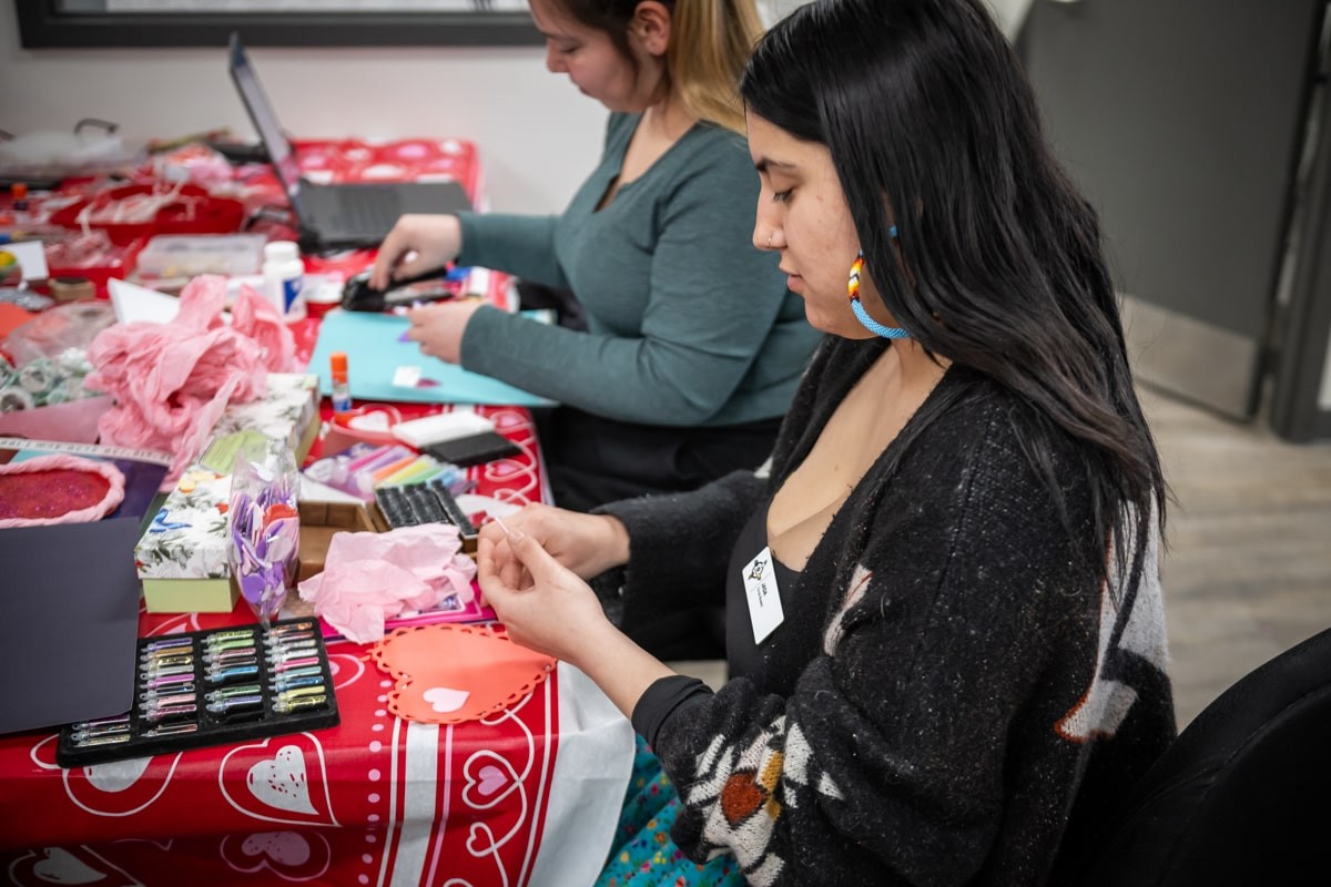 people sit around table making valentine's cards with craft supplies
