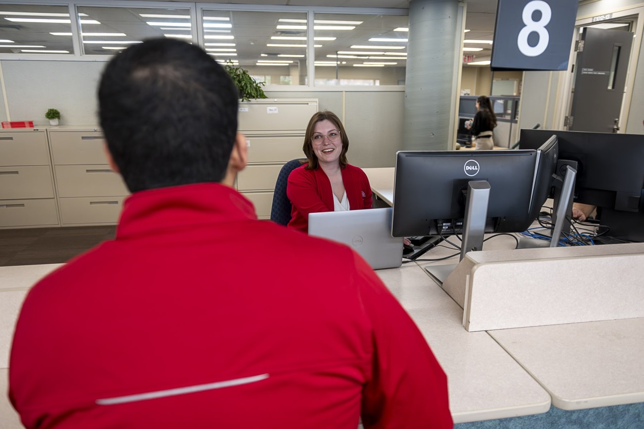 student stands in office of registrar talking to staff