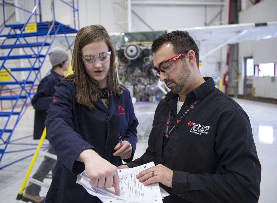 An instructor reviewing aviation information with a student in a flight hanger
